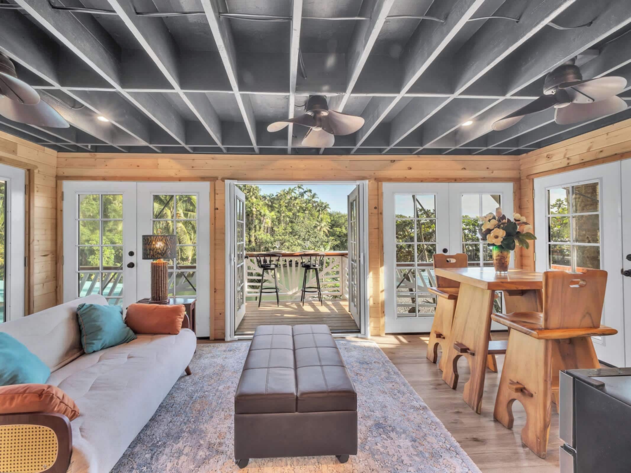 A spacious room with a sofa, ottoman, and a dining area with a table and chairs.