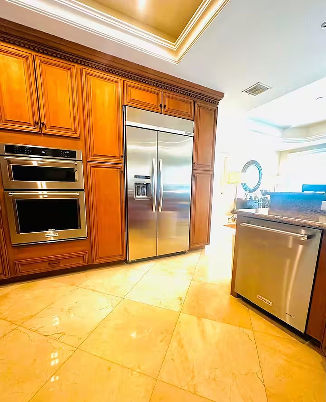 Eine Küche mit Holzausstattung, einem Edelstahlkühlschrank und einem eingebauten Backofen.