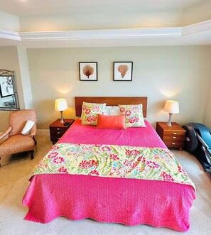 Ein Hotelzimmer mit einem großen Bett, zwei Nachttischlampen, einem Sessel und einem Spiegel.