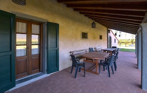 An outdoor patio with a wooden table and chairs, a covered seating area, and a view of the surrounding landscape. - Amazing home in Cortona with private swimming pool, can be inside or outside (Cortona)