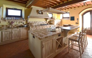 A kitchen with a large island, wooden cabinets, and a tiled backsplash. - Amazing home in Cortona with private swimming pool, can be inside or outside (Cortona)