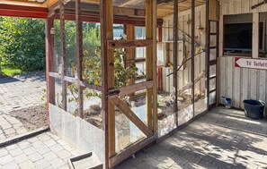 A wooden structure with a mesh enclosure, a sign indicating a toilet, and a paved area with a bucket. - 3 bedroom pet friendly home in Bandholm (Bandholm)