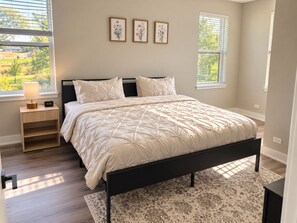Ein Schlafzimmer mit einem Bett, Nachttischen, einem Teppich und gerahmten Bildern an der Wand.