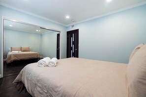 Una habitación de hotel con una cama, un espejo, una puerta y una lámpara en el techo.