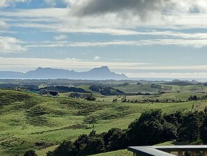 A rural landscape with rolling hills, a distant mountain, and a clear sky.