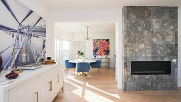 Una cocina moderna con encimera blanca, sillas azules y un cuadro abstracto grande en la pared.