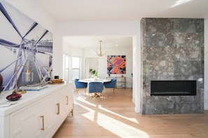 Una cocina moderna con encimera blanca, sillas azules y un cuadro abstracto grande en la pared.