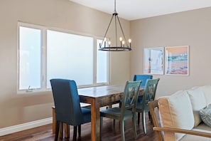 A dining area with a wooden table and chairs, a hanging light fixture, and two framed pictures on the wall. - The Castle Tower Neblina (Oceanside)
