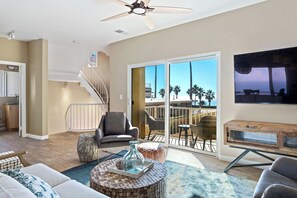 Ein geräumiges Wohnzimmer mit Balkon, einer Treppe und einem Essbereich.