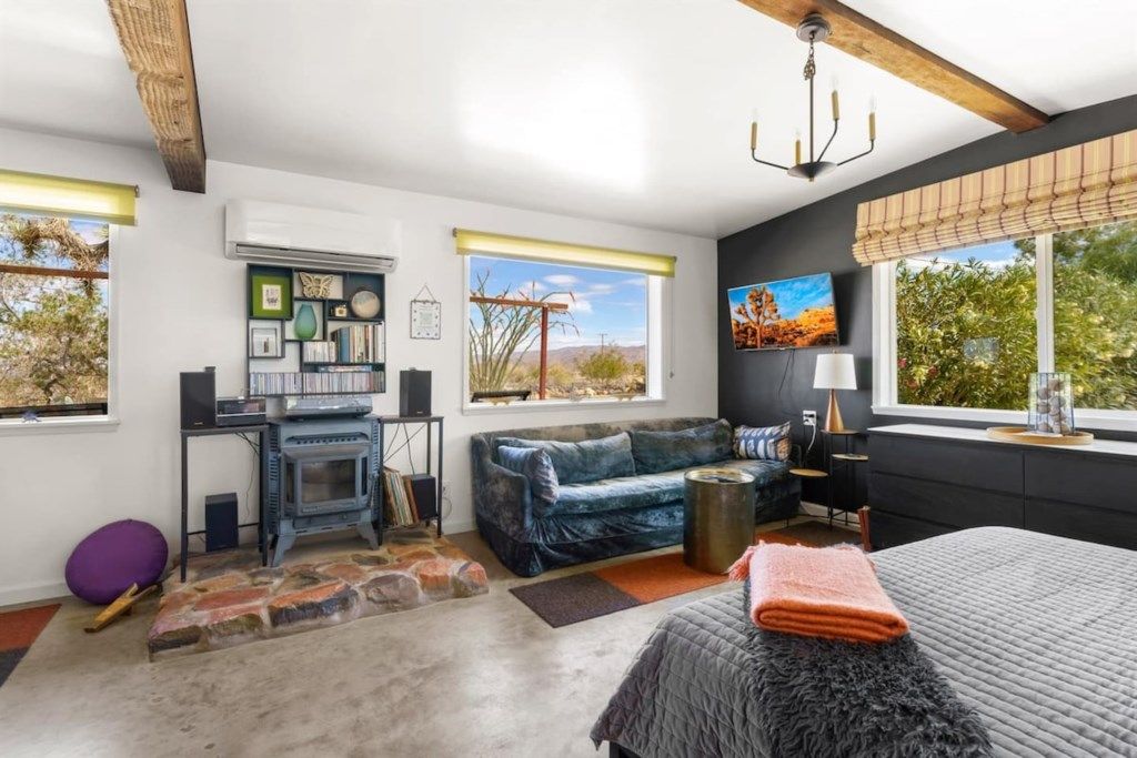 A cozy bedroom with a large bed, a fireplace, and a view of the outdoors.