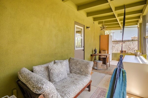 A room with a patterned sofa, a hammock, and a view of the outside.