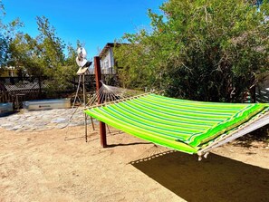 A hammock in a sandy area with a pool and a house in the background. - Tubs, Romantic Views, Quiet, Stars-Serene Haven (Joshua Tree)
