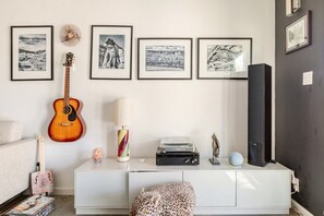 A room with a white cabinet, a guitar, framed pictures on the wall, and a speaker. - Tubs, Romantic Views, Quiet, Stars-Serene Haven (Joshua Tree)