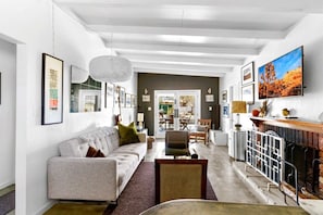 A modern living room with a sofa, coffee table, and fireplace. There is a dining area with a table and chairs visible in the background. - Tubs, Romantic Views, Quiet, Stars-Serene Haven (Joshua Tree)