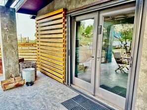 A building entrance with a wooden slatted wall, a metal door, and a concrete floor. - Cowboy Tubs, Quiet, Zen, Stars-1 bd + Studio (Joshua Tree)