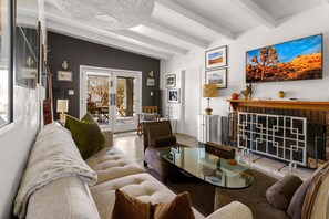 A modern living room with a glass coffee table, a sofa, and a fireplace. - Cowboy Tubs, Quiet, Zen, Stars-1 bd + Studio (Joshua Tree)