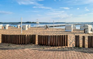 A beach with a wooden fence, a brick walkway, and a pier extending into the water. - Cozy home in Stepnica with WiFi (Stepnica)