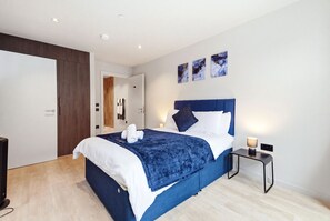 Ein modernes Hotelzimmer mit einem großen Bett, einem Nachttisch mit Lampe und einem Kleiderschrank.