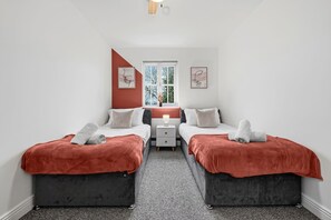 A bedroom with two beds, a window, and artwork on the walls. - House Sleeps 9 With Enclosed Garden (Solihull)