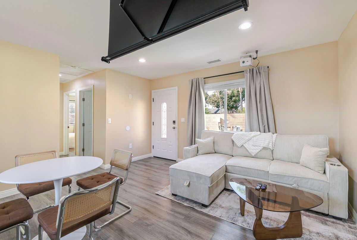Una sala de estar con un sofá modular, una mesa redonda y una mesa de comedor con sillas.