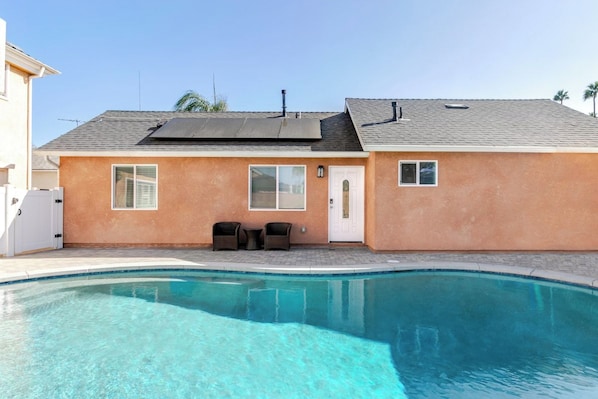 Um imóvel residencial com piscina, uma casa de dois andares e uma pequena área de varanda.