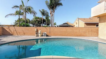 Une piscine avec un mur en briques et des palmiers en arrière-plan.