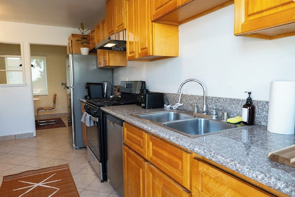 A kitchen with wooden cabinets, a stainless steel sink, a stove, and a refrigerator.