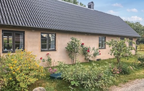 A single-story house with a sloped roof, multiple windows, and a garden with various plants and flowers. - Pet friendly home in Simrishamn with house a panoramic view (Simrishamn)