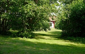 Ein Weg, der zu einem roten Gebäude inmitten dichter grüner Vegetation führt.