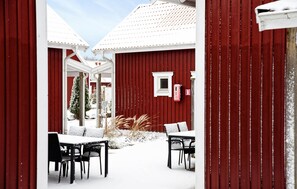 Ein rotes Bauernhaus mit weißer Tür, einem kleinen Fenster und einem Briefkasten.