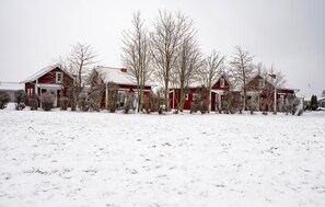 Række af røde huse med snedækkede tage i et sneklædt landskab.