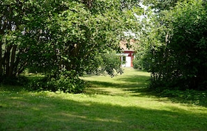 Ein Weg, der zu einem roten Gebäude inmitten dichter grüner Vegetation führt.