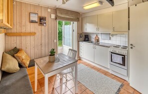 A compact kitchen with a dining area, wooden walls, and a view through a window. - Gorgeous home in Varberg with heated swimming pool (Varberg)