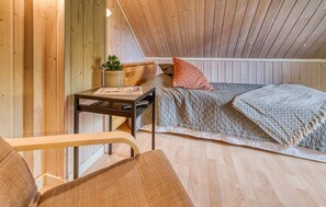 A cozy attic bedroom with a wooden ceiling, a bed with a quilted blanket, a small table with a plant, and a chair. - Gorgeous home in Varberg with heated swimming pool (Varberg)