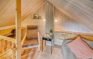 A cozy attic bedroom with a wooden sloped ceiling, a single bed, a chair, a small table with a plant, and a shelf with books. - Lovely home in Varberg with heated swimming pool (Varberg)