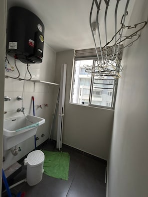 Ein kleines Badezimmer mit Waschbecken, Spiegel, Handtuchhalter und einem Fenster.