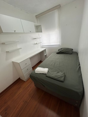 Ein Schlafzimmer mit einem Bett, einem Schreibtisch und einem Kleiderschrank.