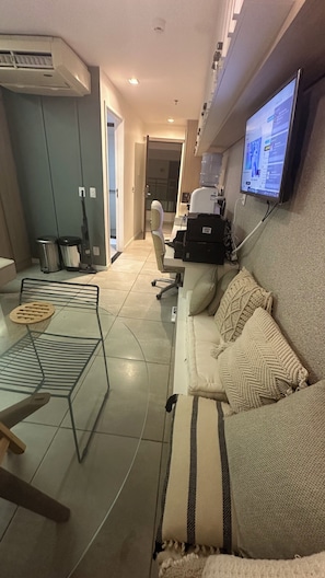 Een moderne woonkamer met een bank, salontafel, een aan de muur bevestigde televisie en een waterdispenser.