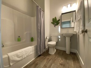 A bathroom with a bathtub, toilet, sink, and a mirror. - Downtown Chattanooga Condo Overlooking Brewery (Chattanooga)