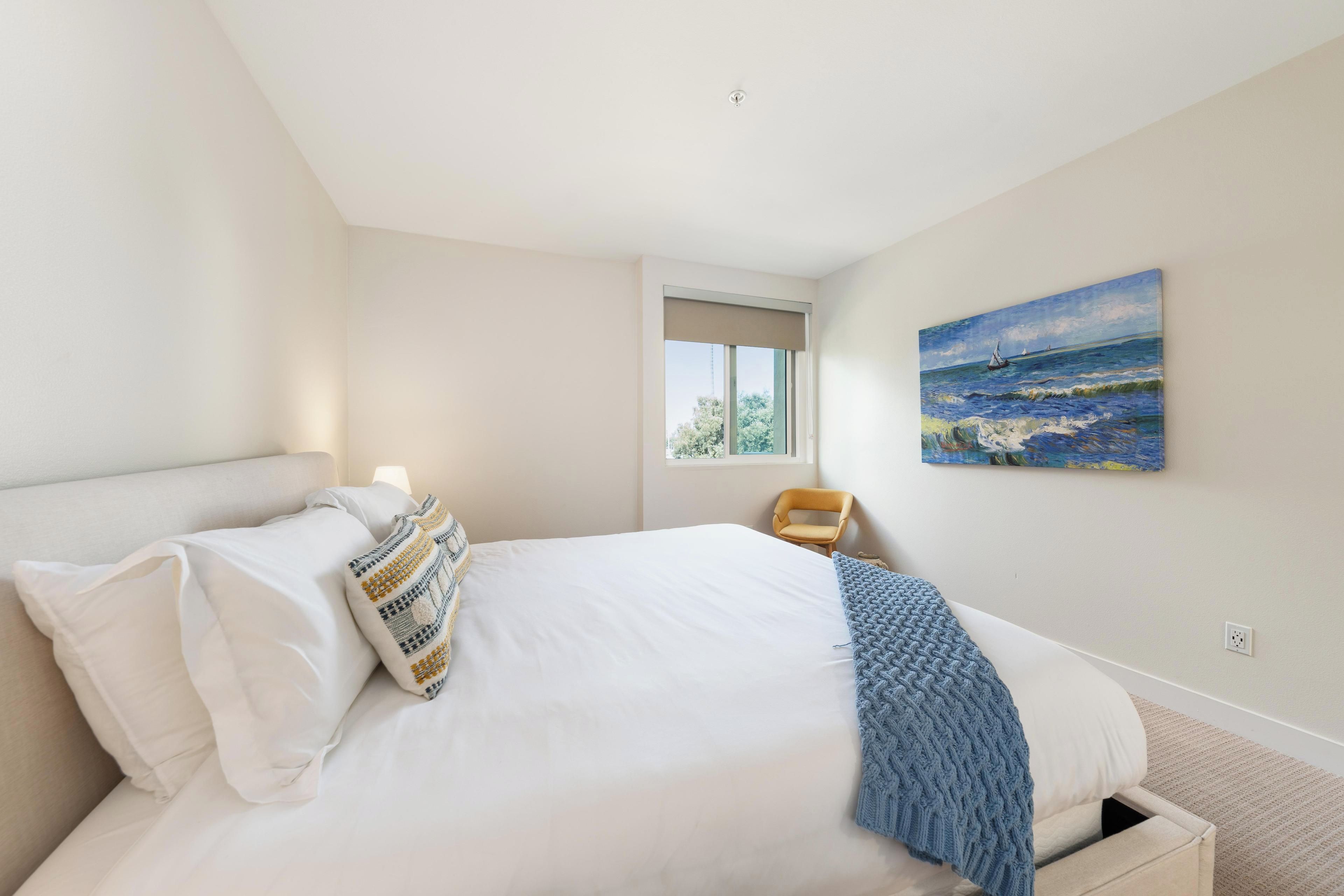 Ein Schlafzimmer mit Bett, Fenster und einem Bild an der Wand.