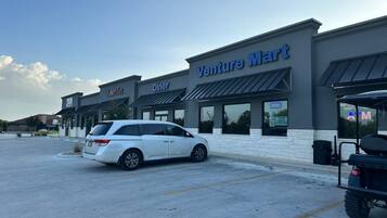 A commercial building with a 'Venture Mart' sign, a 'Diner' sign, and a white car parked in front.
