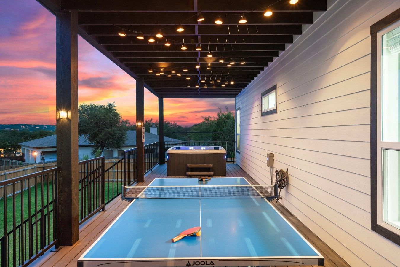 A ping pong table on an outdoor deck with a sunset view.