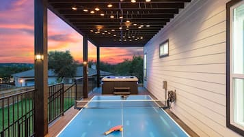 A ping pong table on an outdoor deck with a sunset view.