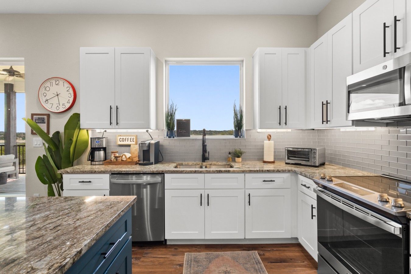 A modern kitchen with white cabinets, a stainless steel dishwasher, a built-in oven, and a coffee station.