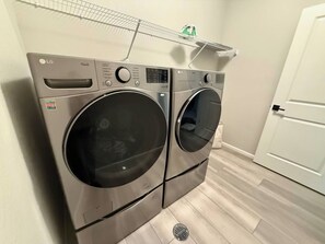 Une buanderie équipée de deux machines à laver et de deux sèche-linge LG ThinQ à chargement frontal, superposés l’un à l’autre.