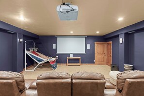A home theater room with a projector, a reclining chair, a small table, and a door. - Summit & Slide Adventure Lodge (Heber City)