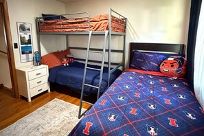 Une chambre de dortoir avec des lits superposés, un bureau et une couvre-lit à motifs.