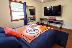 A room with a bed, a TV, a desk, and a window. - The Illini House - UIUC Game Day Getaway (Urbana)