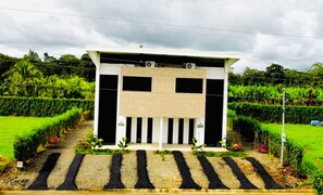A modern building with a flat roof, rectangular windows, and a paved entrance with a striped pattern.