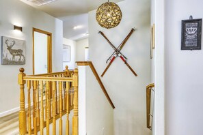 Eine Treppe mit Holzbalustern, einem an der Wand befestigten Kruzifix und einem Bilderrahmen mit einem Reh.